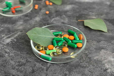 Dish with plant based pills on grunge background