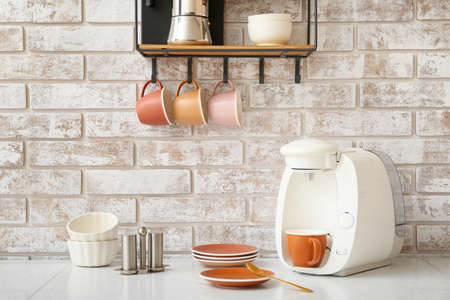 Shelf with cups and coffee machine on table in kitchenの写真素材