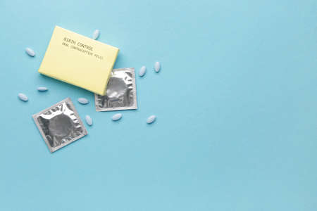 Contraceptive pills and condoms on color backgroundの写真素材