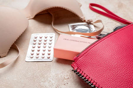 Female bag with contraceptive pills, condom and bra on gray backgroundの写真素材
