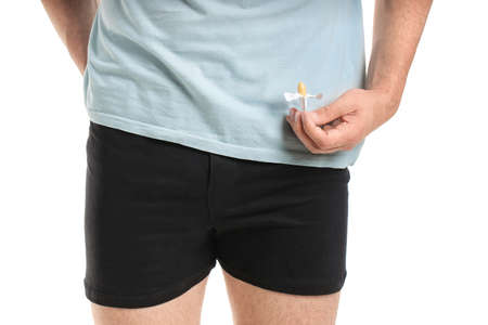 Young man with hemorrhoidal suppository on white background, closeupの写真素材