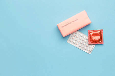 Contraceptive pills and condom on color backgroundの写真素材