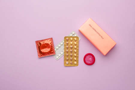 Contraceptive pills and condoms on color backgroundの写真素材