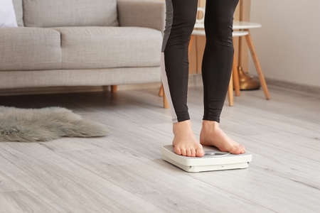 Young woman measuring her weight at homeの写真素材