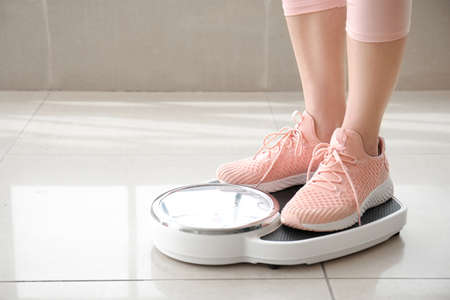 Young woman measuring her weight at homeの写真素材