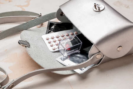 Female bag with contraceptive pills, condoms and cosmetics on white backgroundの写真素材
