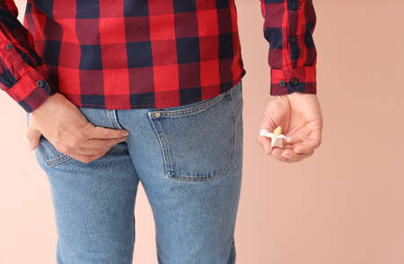 Young man with hemorrhoidal suppository on color backgroundの写真素材