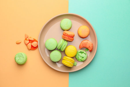 Tasty macarons with plate on color backgroundの写真素材