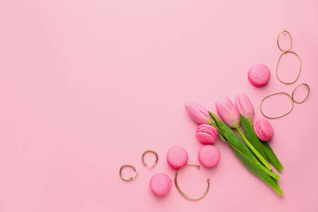 Tasty macarons with jewelry and tulip flowers on color backgroundの写真素材