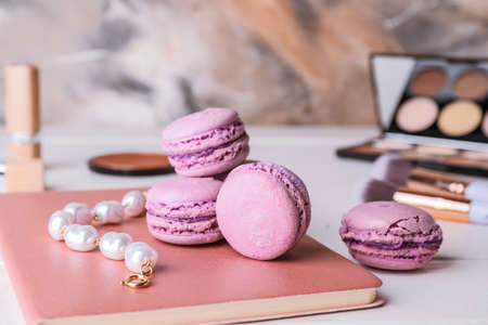 Notebook with tasty macarons and jewelry on tableの写真素材