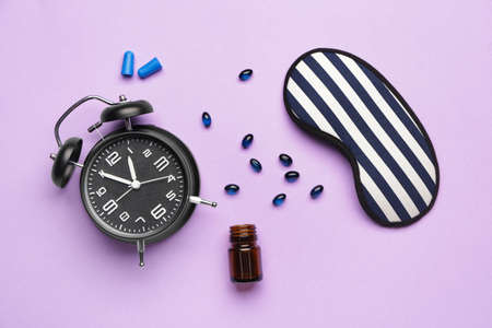 Sleep mask, alarm clock and pills on color backgroundの写真素材