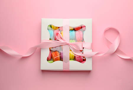 Gift box with tasty macarons on color backgroundの写真素材