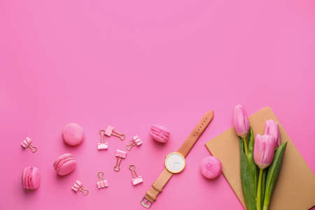 Stationery and clock with tasty macarons on color backgroundの写真素材
