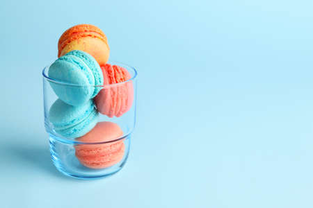 Tasty macarons in glass on color backgroundの写真素材