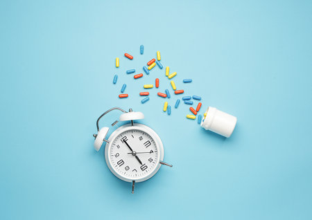 Composition with sleeping pills and alarm clock on color backgroundの写真素材