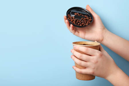 Female hand with takeaway cup of coffee on color backgroundの写真素材