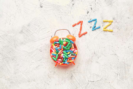 Alarm clock and sleeping pills on light backgroundの写真素材