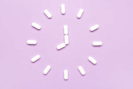 Clock made of sleeping pills on color backgroundの写真素材
