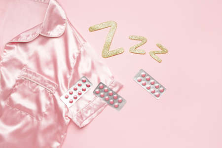Composition with pajamas and sleeping pills on color background