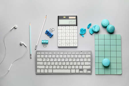 Stationery and computer keyboard with tasty macarons on white backgroundの写真素材