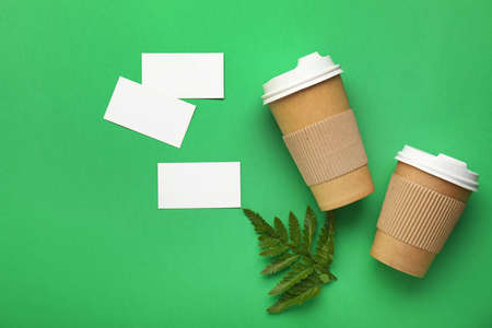 Takeaway coffee cups with business cards on color backgroundの写真素材