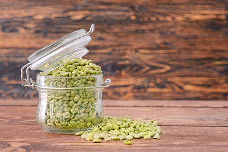 Jar with green coffee beans on tableの写真素材