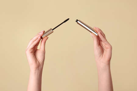 Female hands with mascara on color backgroundの写真素材