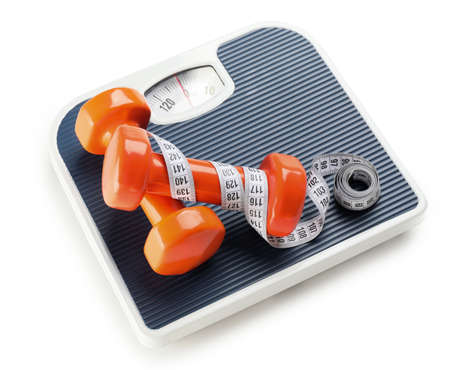 Weight scales with measuring tape and dumbbells on white background. Slimming concept