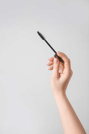 Female hand with mascara on gray backgroundの写真素材