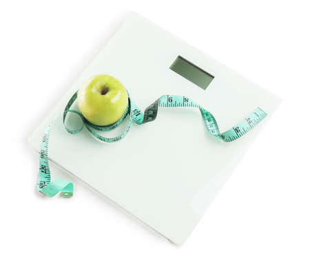 Weight scales with measuring tape and apple on white background. Slimming conceptの写真素材