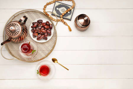 Tasty Turkish tea with dates, Koran and tasbih on tableの写真素材
