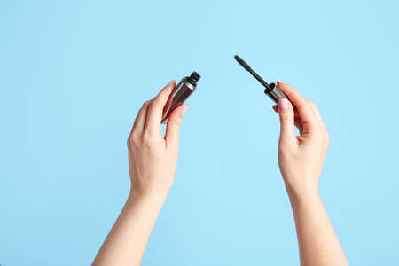 Female hands with mascara on color backgroundの写真素材