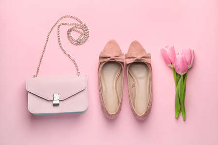 Stylish bag with female shoes and flowers on color backgroundの写真素材