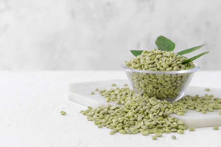 Bowl with green coffee beans on tableの写真素材