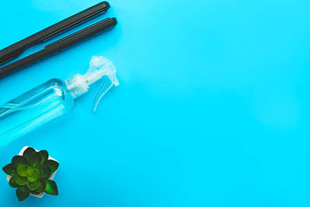 Hair spray with flat iron on color backgroundの写真素材