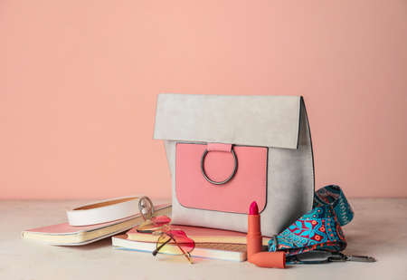 Stylish bag with female accessories and notebooks on tableの写真素材