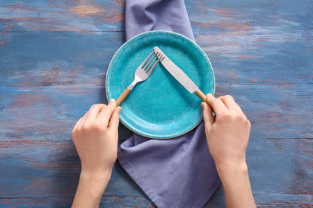 Woman at table with clean plate and cutlery, top viewの写真素材