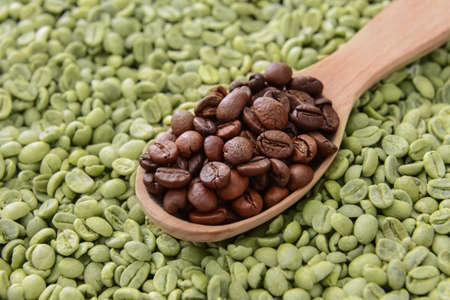 Spoon with roasted and green coffee beansの写真素材