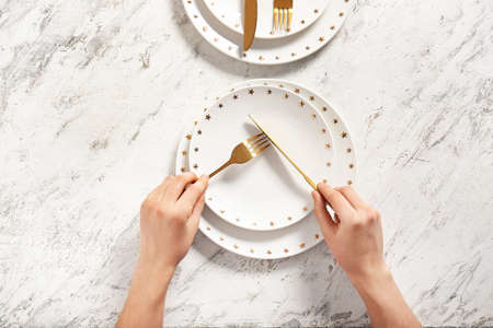 Woman at table with clean plates and cutlery, top viewの写真素材