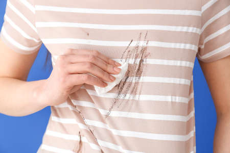 Woman in dirty clothes and with napkin on color background, closeupの写真素材