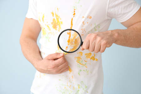 Man in dirty clothes and with magnifying glass on color background, closeupの写真素材