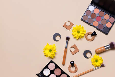 Makeup cosmetics with earrings on gray background