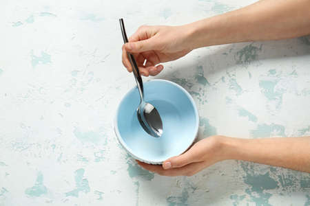 Woman at table with clean bowl and spoon, top viewの写真素材