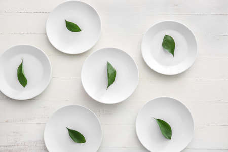 Clean plates with leaves on white wooden backgroundの写真素材