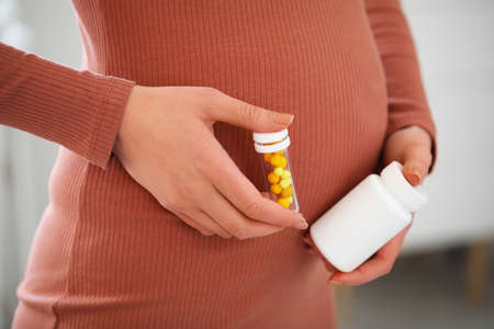 Young pregnant woman with medicines at home, closeupの写真素材