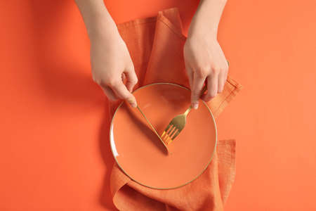 Woman at table with clean plate and cutlery, top viewの写真素材
