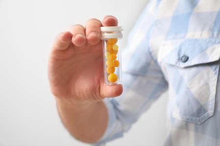 Young man with pills on light background, closeupの写真素材