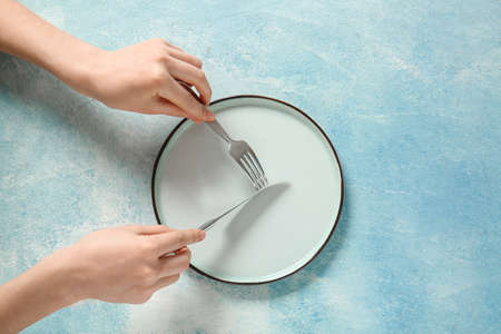 Woman at table with clean plate and cutlery, top viewの写真素材