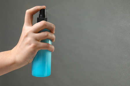 Female hand with hair spray on gray backgroundの写真素材