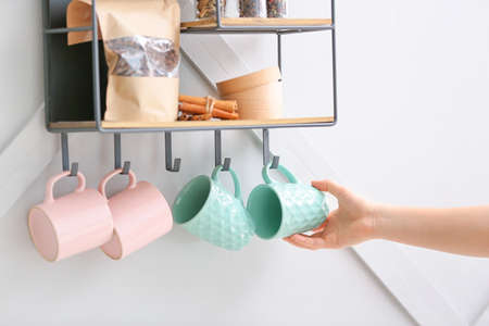 Woman hanging cup on shelf with kitchenwareの写真素材